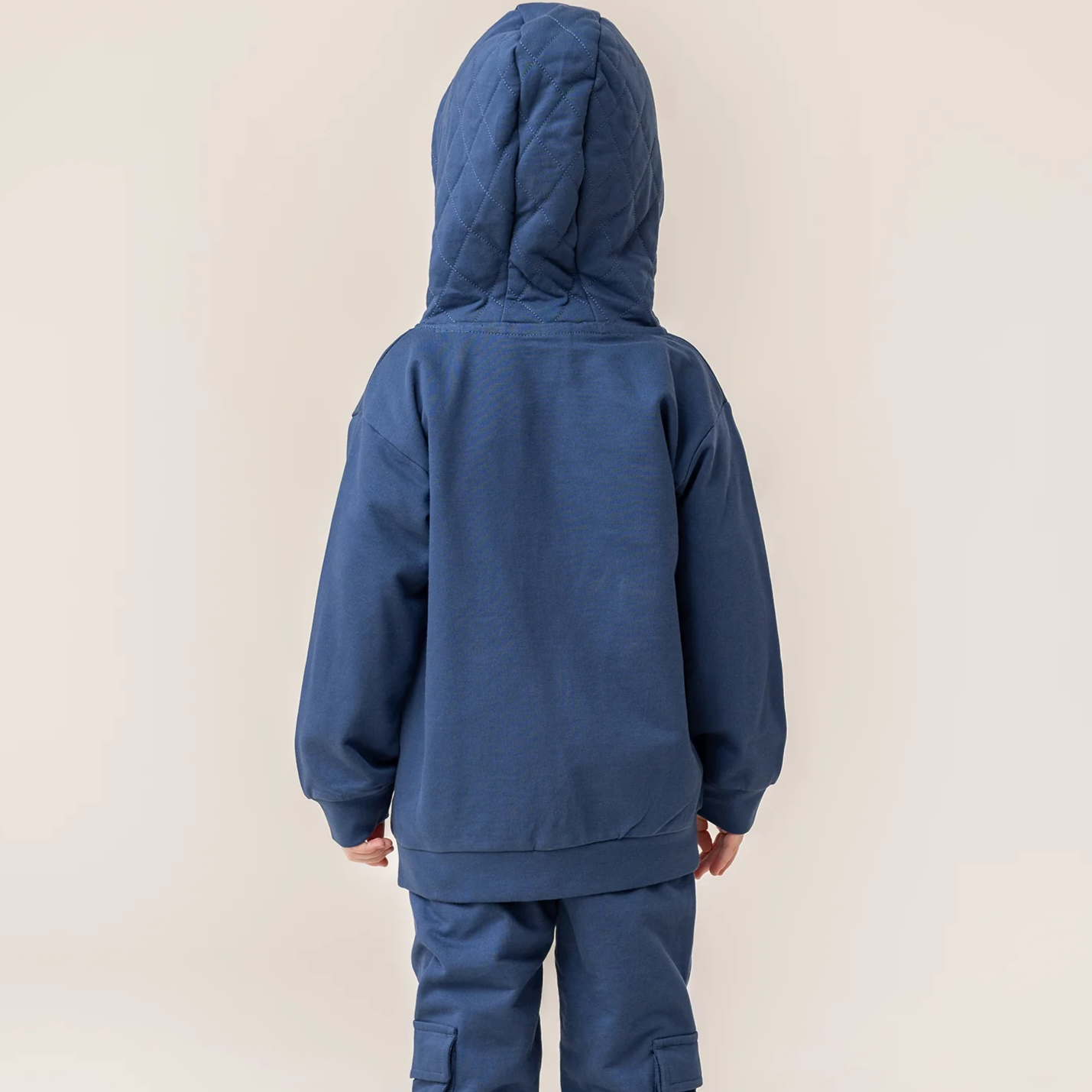 Person wearing a blue tracksuit on a beige background