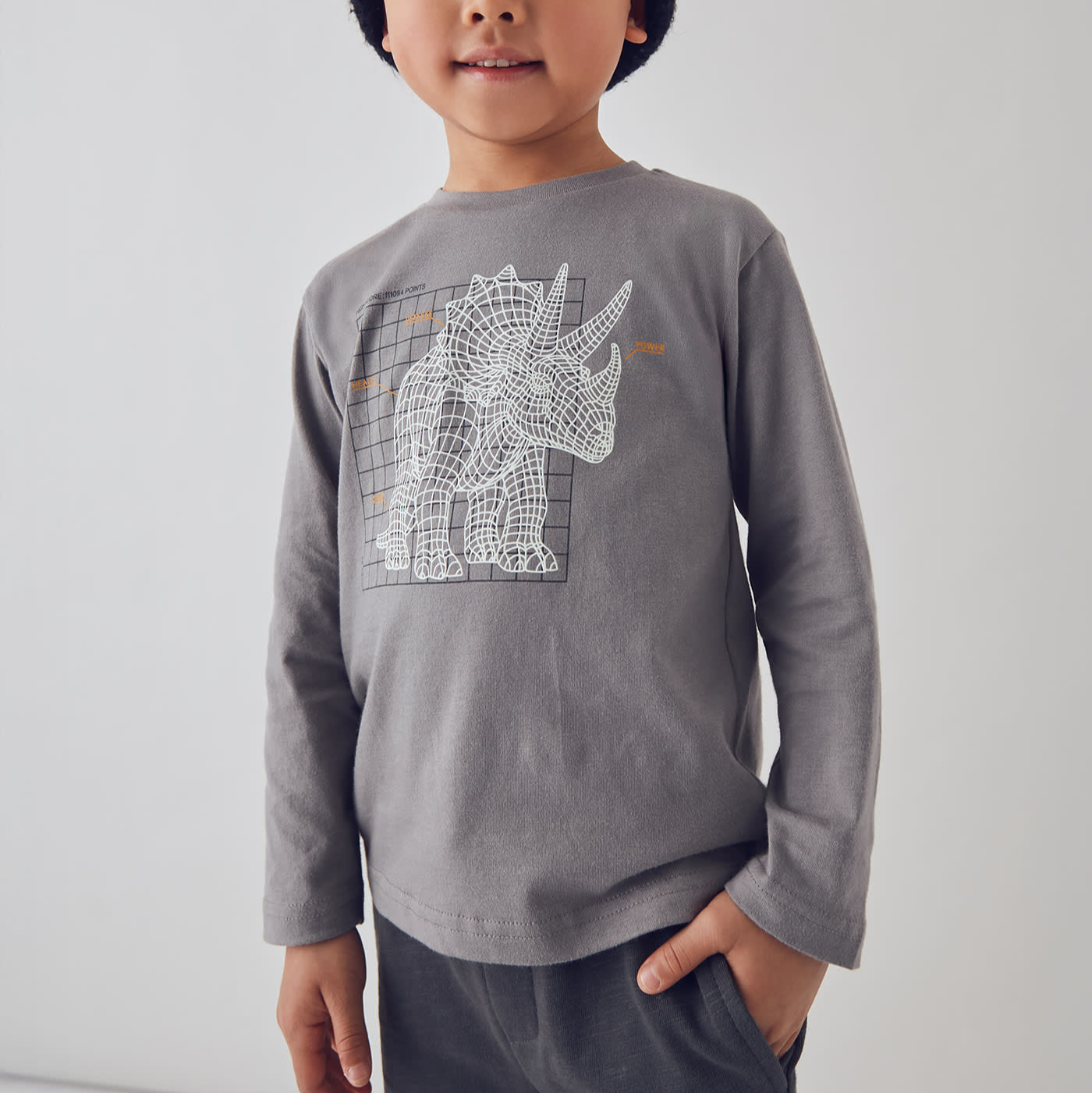 Child wearing a gray long-sleeve shirt with a white graphic design on a plain background