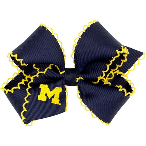 Navy blue hair bow with yellow trim and 'M' logo on a white background