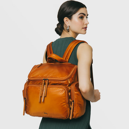 Woman wearing an orange backpack on a plain background