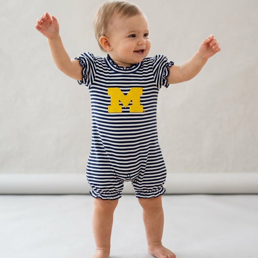 A baby girl's short-sleeve bubble romper with navy and white horizontal stripes, featuring a large yellow 'M' logo on the chest representing the University of Michigan, set against a plain white background.