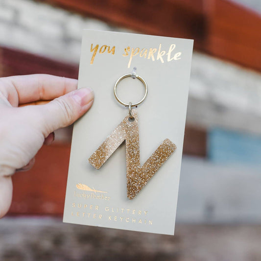 Gold glittery keychain with 'you sparkle' card held by a hand