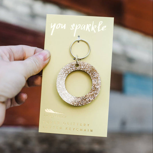 Gold hoop earring on a card held by a hand with a blurred background