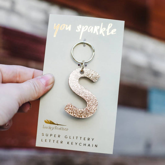 Rose gold glittery letter 'S' keychain on a card with 'you sparkle' text.