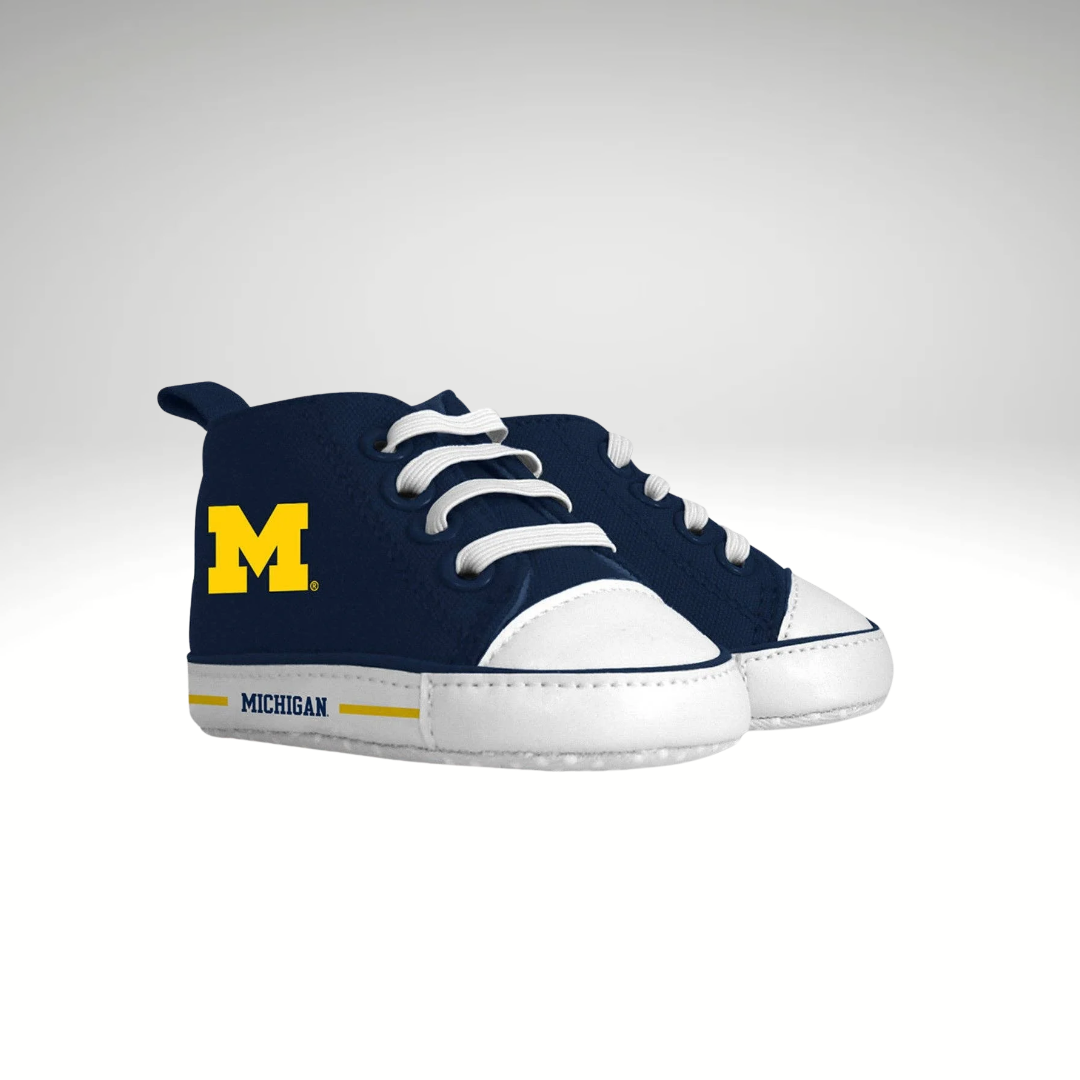 A pair of baby high-top sneakers in navy blue and white, featuring the yellow Michigan 'M' logo on the side and 'MICHIGAN' text on the white sole.
