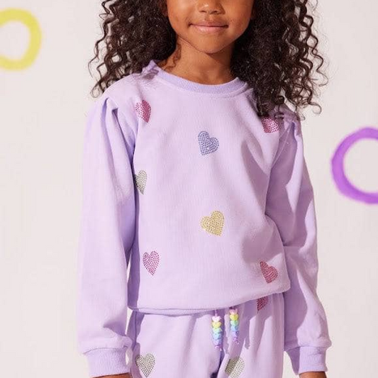 Child wearing a purple outfit with heart patterns on a white background